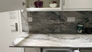 A kitchen with white cabinets, a marble countertop, and a built-in refrigerator. - Room-cosy Small Double Room in Quiet Sha (Chelmsford)