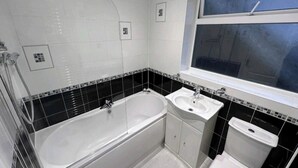 A bathroom with a bathtub, a sink, and a toilet. - Room-cosy Small Double Room in Quiet Sha (Chelmsford)