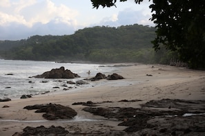 A beach with rocky outcrops and a forested hillside in the background. - Ocean View Studio at Taru Rentals (Montezuma)