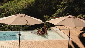 A pool area with lounge chairs and umbrellas. - Ocean View Studio at Taru Rentals (Montezuma)