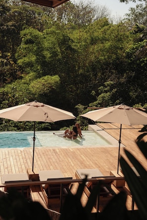A pool area with lounge chairs and umbrellas. - Ocean View Studio at Taru Rentals (Montezuma)