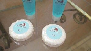 Dos botellas de champú acondicionador Ocean Blue y dos pastillas de jabón en una vitrina de cristal.