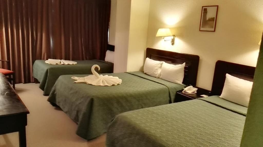 A hotel room with two beds, a desk, a lamp, and a telephone on the nightstand.