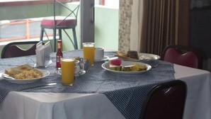 Una mesa dispuesta con platos de desayuno, vasos de jugo de naranja y una botella de agua.