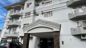 A multi-story building with a central entrance, air conditioning units, and a paved driveway. - sunset inn canasvieiras (Florianópolis)