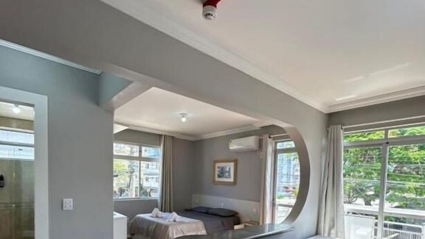 A modern bedroom with a large bed, a small table, and a curved wall. - sunset inn canasvieiras (Florianópolis)