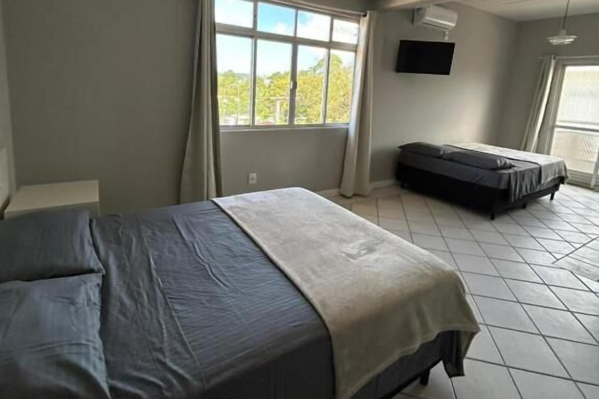 Una camera da letto con un letto, una finestra, una TV e una ventola a soffitto.