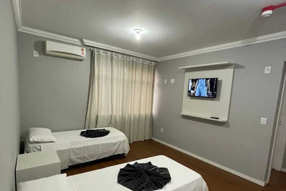 Una stanza con due letti, una TV e un condizionatore.