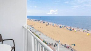 A balcony with a view of a beach, a chair, and a table. - Boardwalk Villas Resort Oceanview condo with Oceanfront Balcony (Virginia Beach)