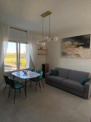 Ein Essbereich mit einem runden Tisch, Stühlen, einer Couch und einem Gemälde an der Wand.