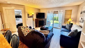 Una sala de estar con sofá, televisión, chimenea y comedor con sillas y mesa.