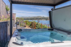 A hot tub with a view of a lake and hills.