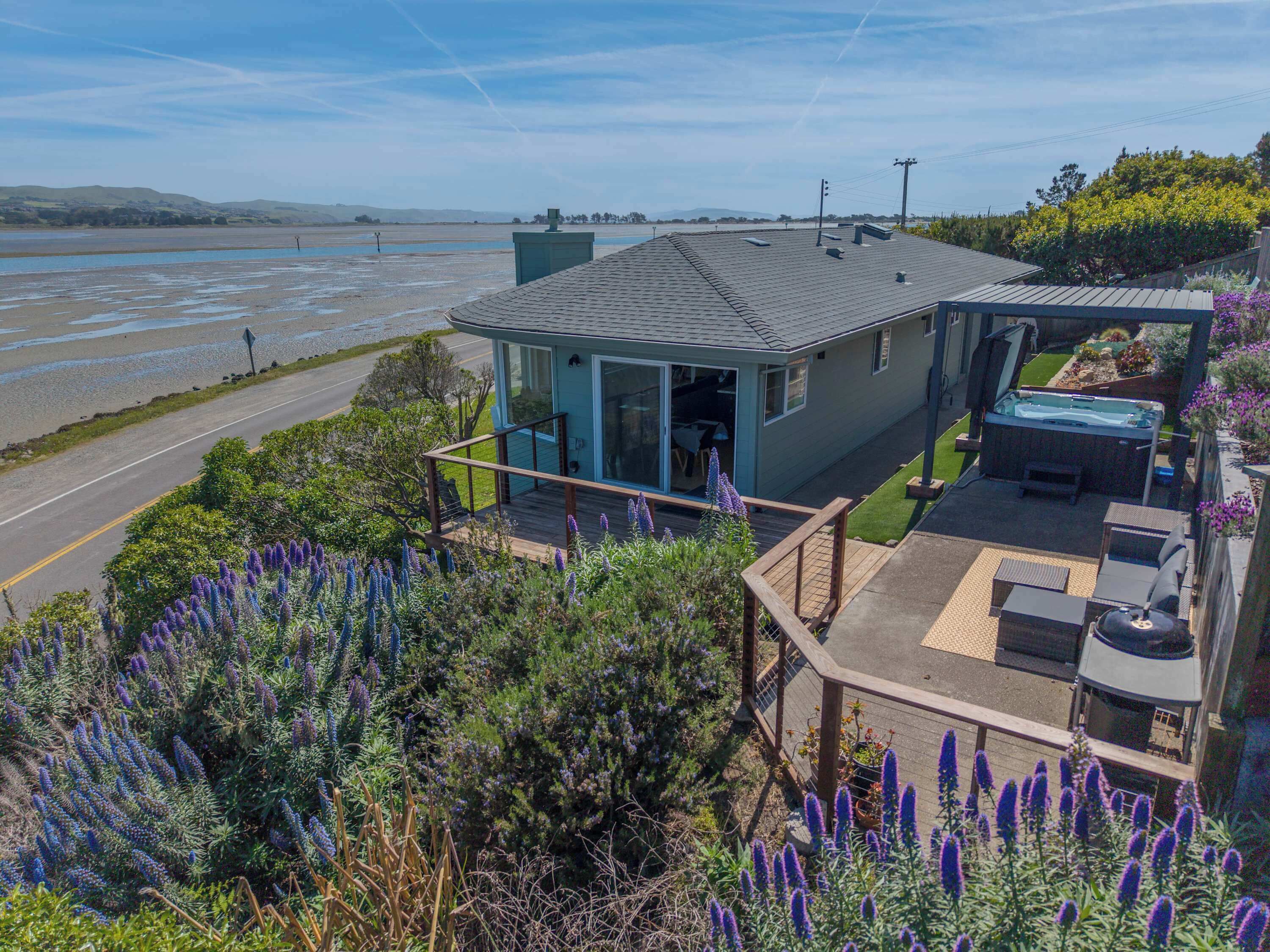 A house with a deck, a hot tub, and a view of the water.