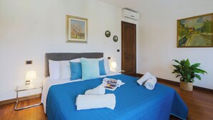 A hotel room with a bed, a nightstand, a lamp, a potted plant, and two paintings on the walls. - 2-bedroom condo in peaceful Lucca with air conditioning and assigned parking (Lucca)