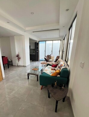 A spacious living room with a sofa, coffee table, and a view through a sliding glass door. - 3-bedroom house in fantastic Santo Domingo Este with AC (Santo Domingo Este)