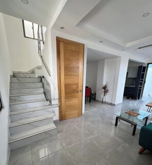 A modern interior with a marble staircase, a wooden door, a glass coffee table, and a dining area. - 3-bedroom house in fantastic Santo Domingo Este with AC (Santo Domingo Este)