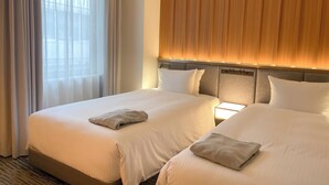 Een hotelkamer met twee bedden, een groot raam met gordijnen en een houten hoofdeinde.