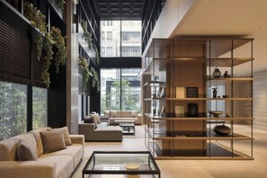 A modern living room with a sofa, coffee table, and a bookshelf. - Sugata Hotel Osaka Shinsaibashi, Series By Marriott (Osaka)