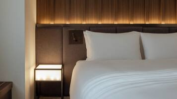Una habitación de hotel con una cama grande, una mesita de noche con una lámpara y un cabecero de madera.