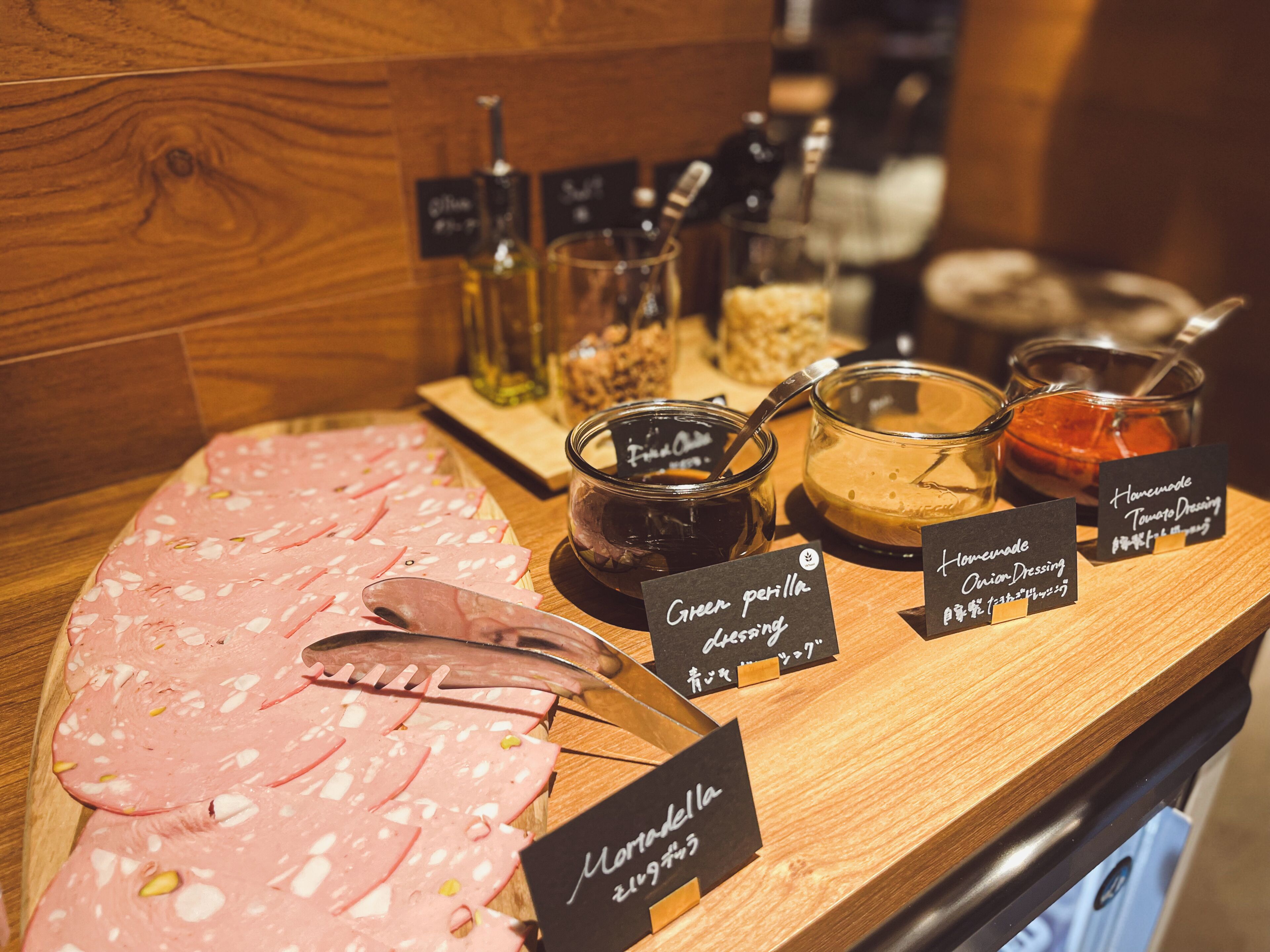 A deli counter with various meats and condiments, including labels for 'Green pepper dressing' and 'Homemade Tomato Dressing'.