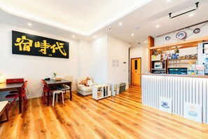 Un interior moderno con piso de madera, un área de comedor con mesa y sillas, un sofá con un juguete de jirafa y una recepción con varios objetos.