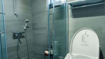A modern bathroom with a glass-enclosed shower, a toilet, and a small sink.