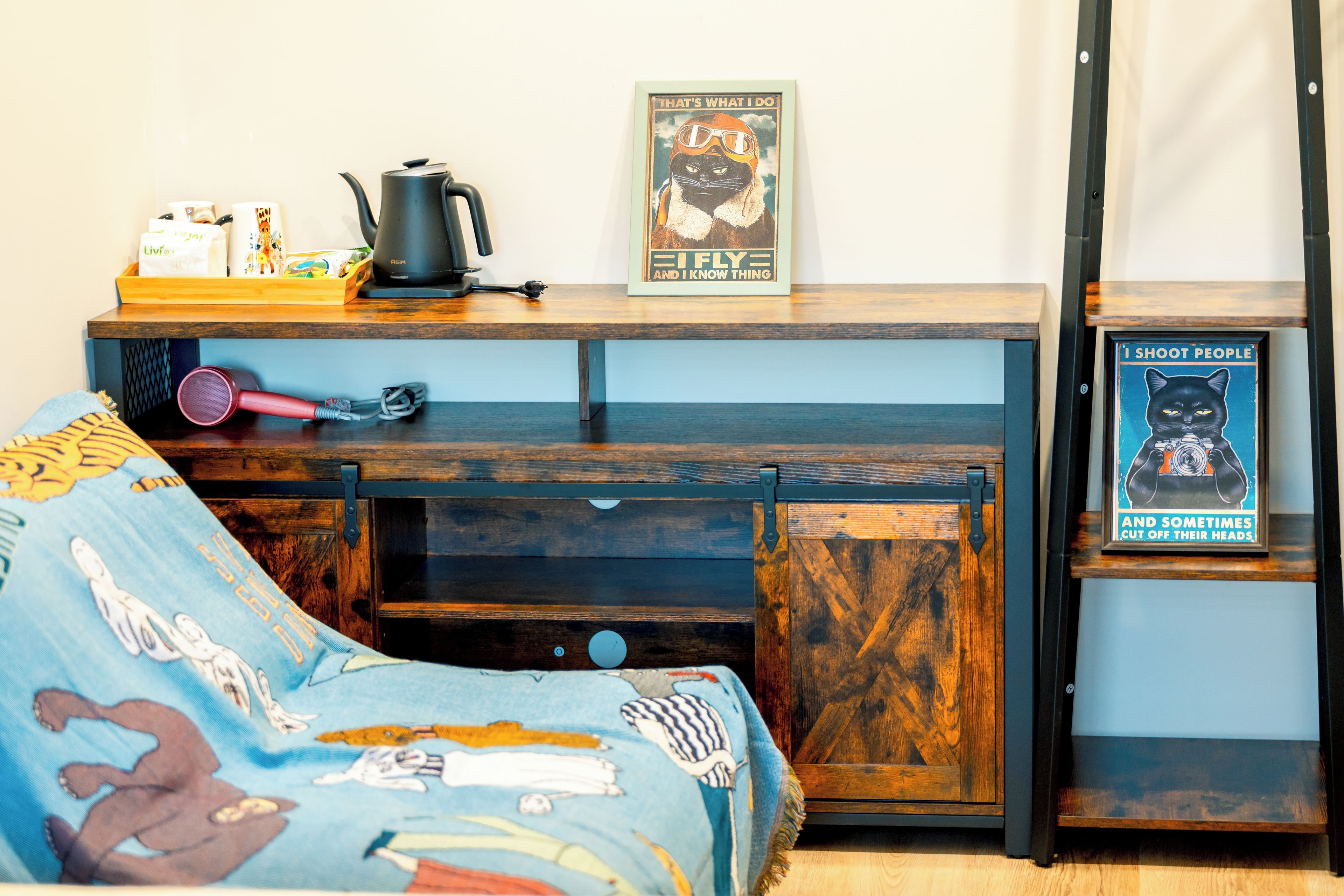 A bedroom with a bed, a desk, and a shelf with various items including a framed poster.