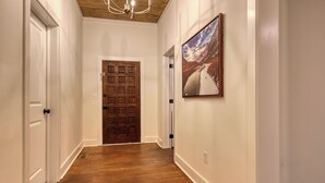 Ein Flur mit Holzboden, weißen W änden, einer Holztür und einem gerahmten Bild an der Wand.