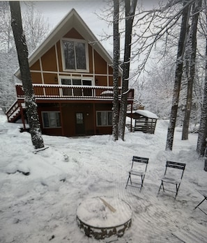Eine Hütte mit Balkon, umgeben von schneebedeckten Bäumen.
