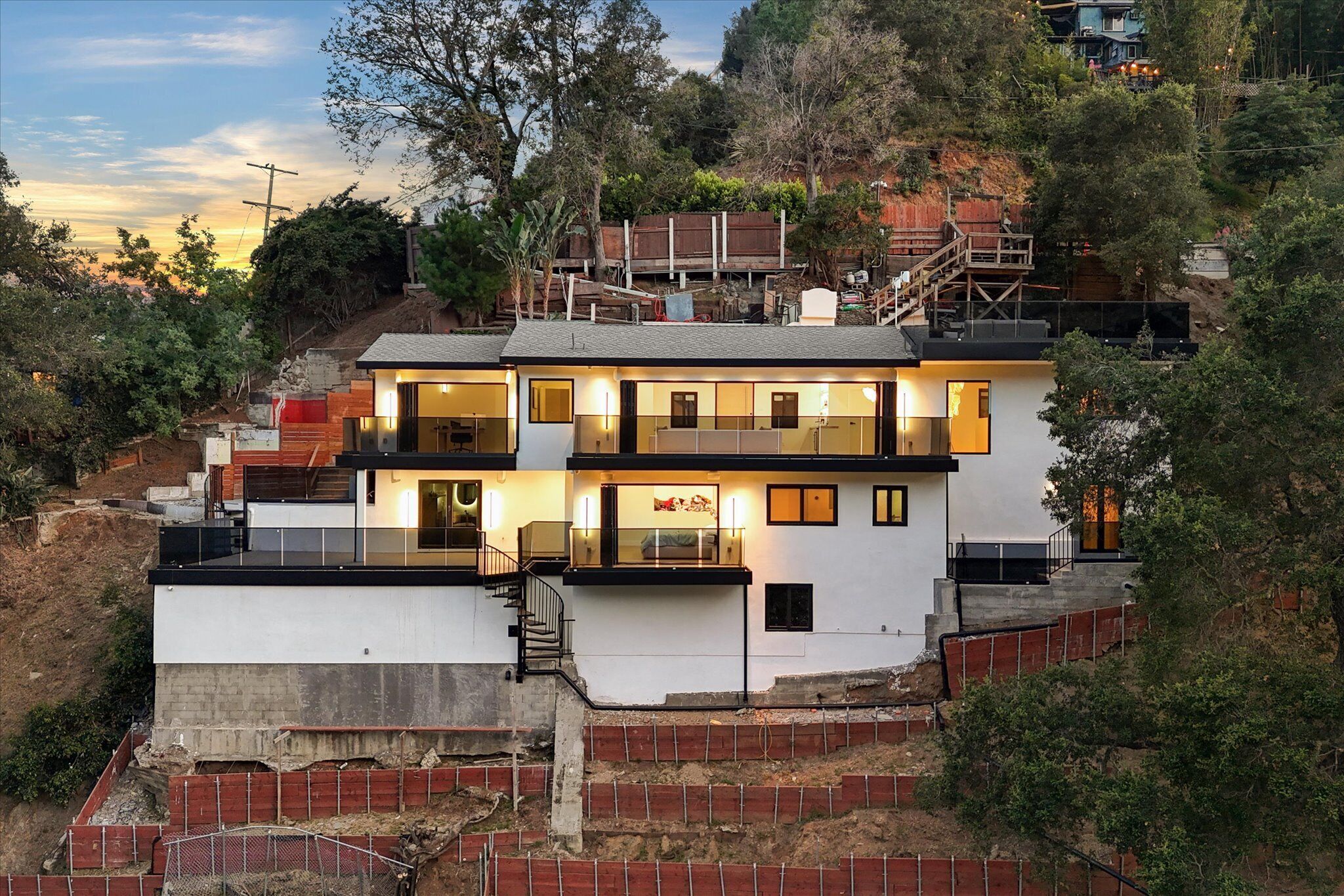 A modern two-story house with a balcony, a staircase, and a view of the surrounding landscape.