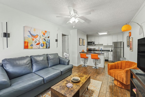 A modern living room with a gray sofa, a wooden coffee table, and an orange armchair.