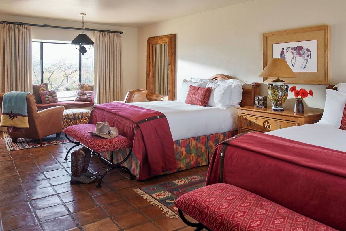 Habitación de hotel con una cama grande, una silla, un escritorio y una ventana con cortinas.