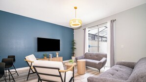 A modern living room with a flat-screen TV, two sofas, a coffee table, and a potted plant. - Championsgate Blue Villa + Private Pool + Resort Access (Davenport)