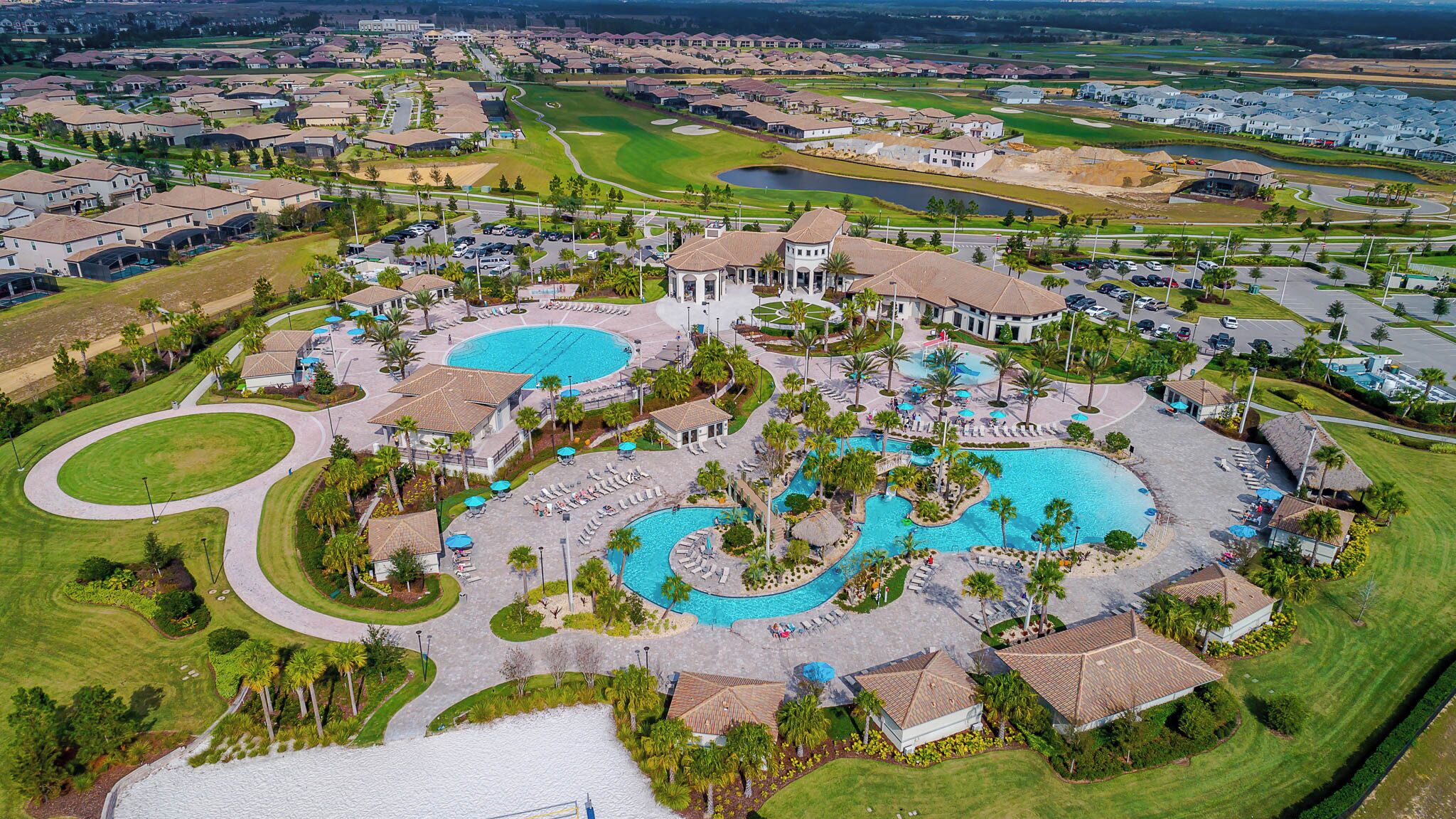 Ein Resort mit mehreren Schwimmbecken, einem Golfplatz und einem großen Parkplatz.