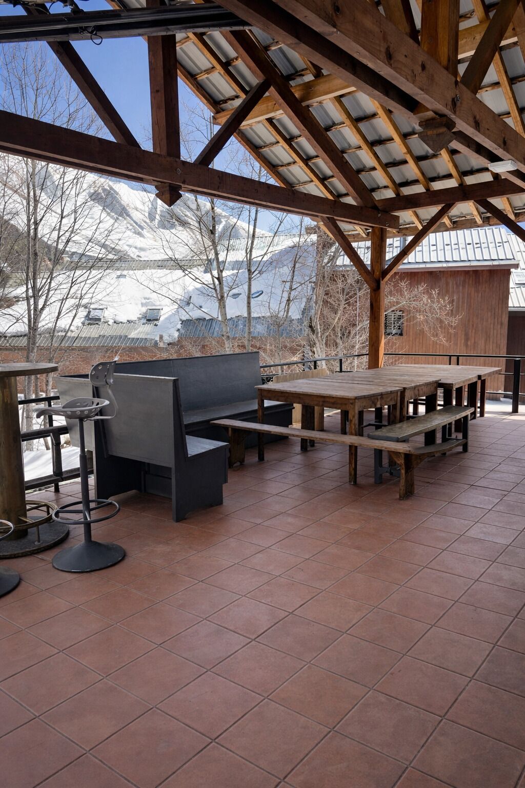 Une terrasse extérieure dotée de bancs en bois et d’une structure à plafond haut.
