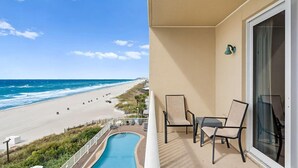 A balcony with a view of the beach, a pool, and two chairs. - Seychelles 603 (Panama City Beach)