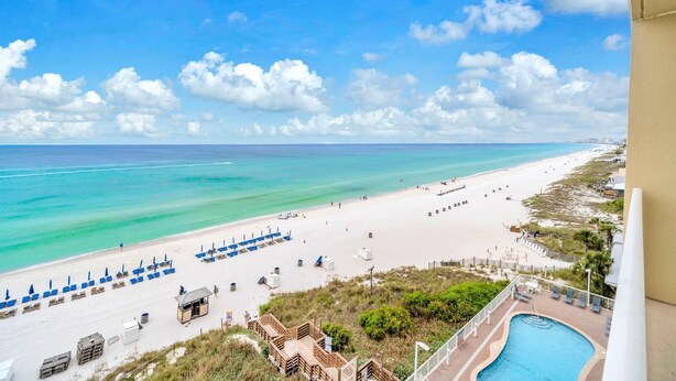 A beach view with a pool, lounge chairs, and a lifeguard tower. - Seychelles 603 (Panama City Beach)