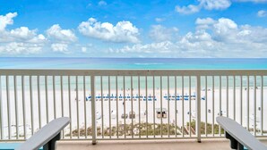 A beach view from a balcony with a railing, a clear sky, and a sandy beach with umbrellas and lounge chairs. - Seychelles 603 (Panama City Beach)