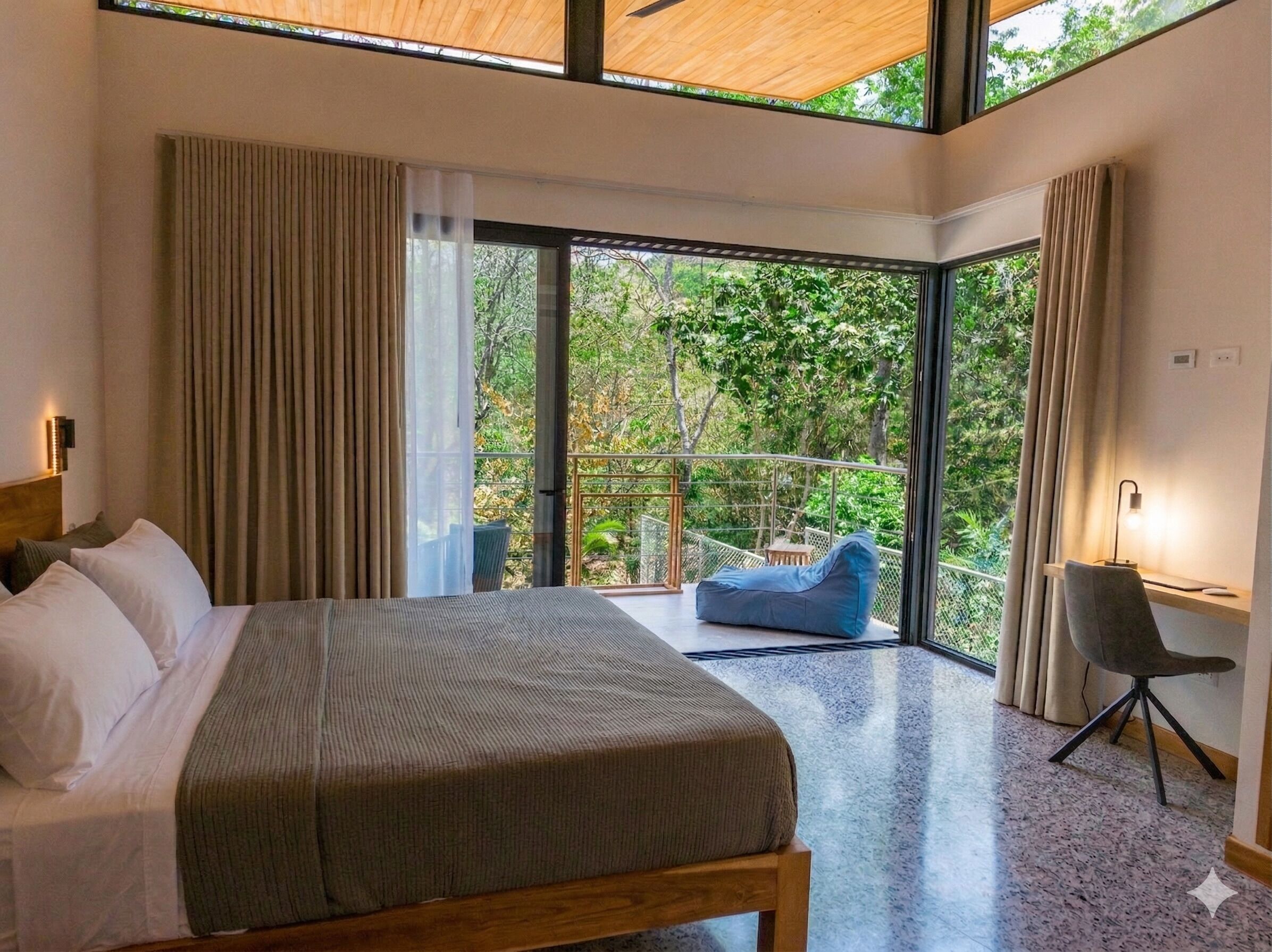 Ein modernes Schlafzimmer mit einem großen Bett, einem Schreibtisch und einem Balkon mit Blick auf Bäume.