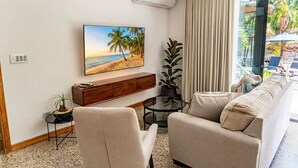Ein Wohnzimmer mit einem Strandbild, einer Couch, einem Couchtisch und einem Blumentopf.