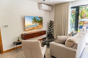 A living room with a beach-themed painting, a sofa, a coffee table, and a potted plant. - New Private Villa · Sleeps 12 · Saltwater Pool, Yoga Deck, BBQ + Daily Service (Tamarindo)