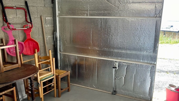 A compact, enclosed space with a metal door, a small table with chairs, and a pink shovel hanging on the wall. - Very Cozy 1-Bedroom Apartment with a Panoramic View (Les Angles)