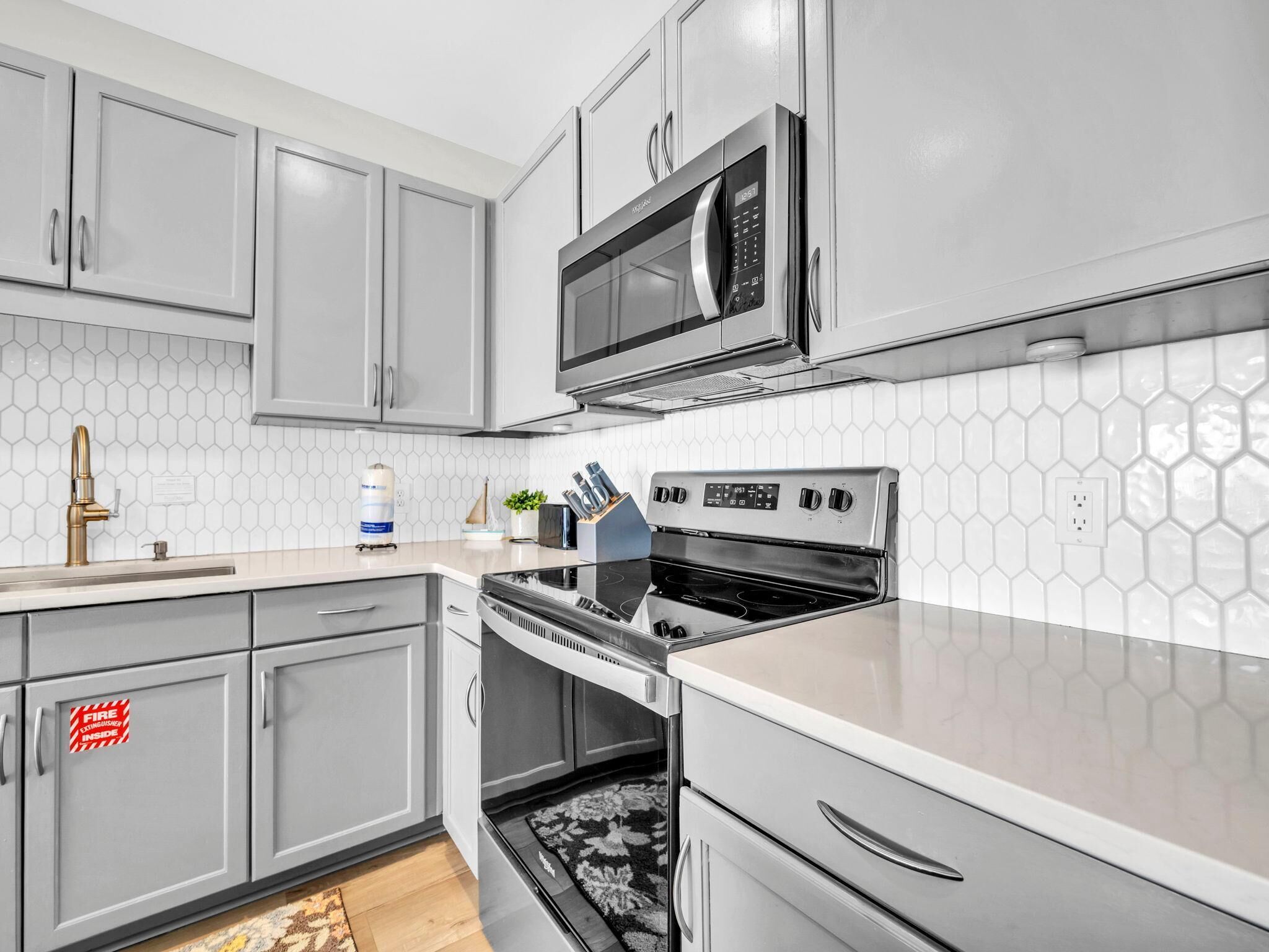 A modern kitchen with grey cabinets, a stainless steel stove, and a microwave.