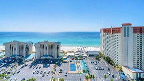 A hotel complex with multiple buildings, a parking lot, and a beach in the background. - Ocean Villa Penthouse 2306 (Panama City Beach)