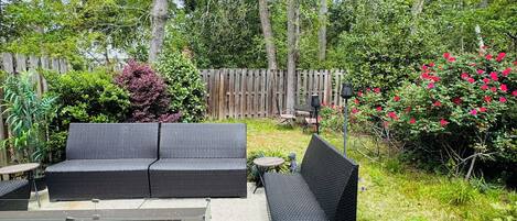 An outdoor patio area with a sofa set, a table, and a fire pit.