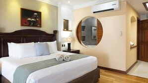 A hotel room with a large bed, a round mirror, a painting on the wall, and a wooden floor. - Beachfront with pier and saltwater pool for 14 ppl 4 bedrooms (Cozumel)
