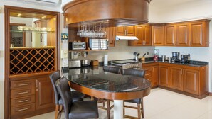 A kitchen with a central island, wooden cabinets, a microwave, and a stove. - Beachfront with pier and saltwater pool for 14 ppl 4 bedrooms (Cozumel)