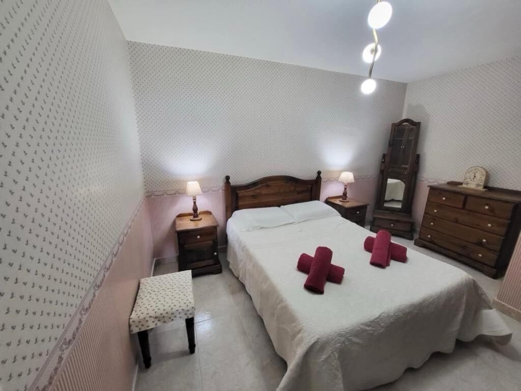 A bedroom with a bed, bedside tables, a nightstand, a dresser, and a mirror.