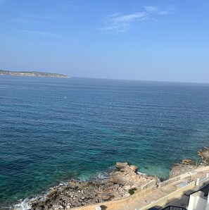 A coastal view with clear blue sea, rocky shoreline, and a distant landmass. - Unique Seafront Apartment in Mellieha - Seafront Balcony !! Amazing Views !! (Il-Mellieħa)
