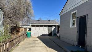A narrow concrete pathway leading to a garage with a wooden fence on one side and a house on the other. - Elmira 1-bedroom guesthouse in beautiful Aurora (Aurora)
